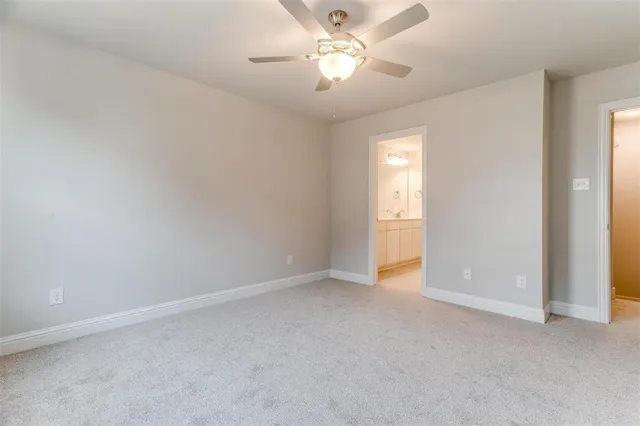an empty room with windows and ceiling fan