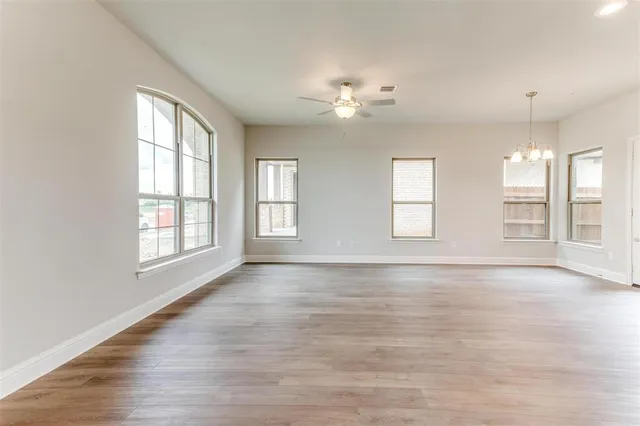 an empty room with wooden floor closet and windows