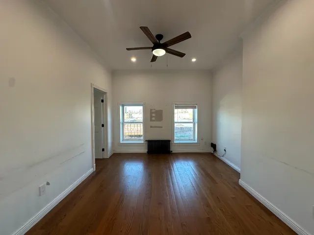 an empty room with wooden floor and windows