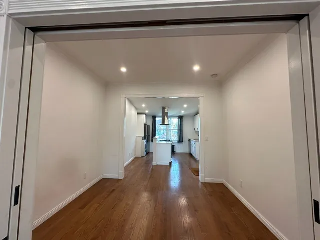 a view of a hallway with wooden floor and staircase