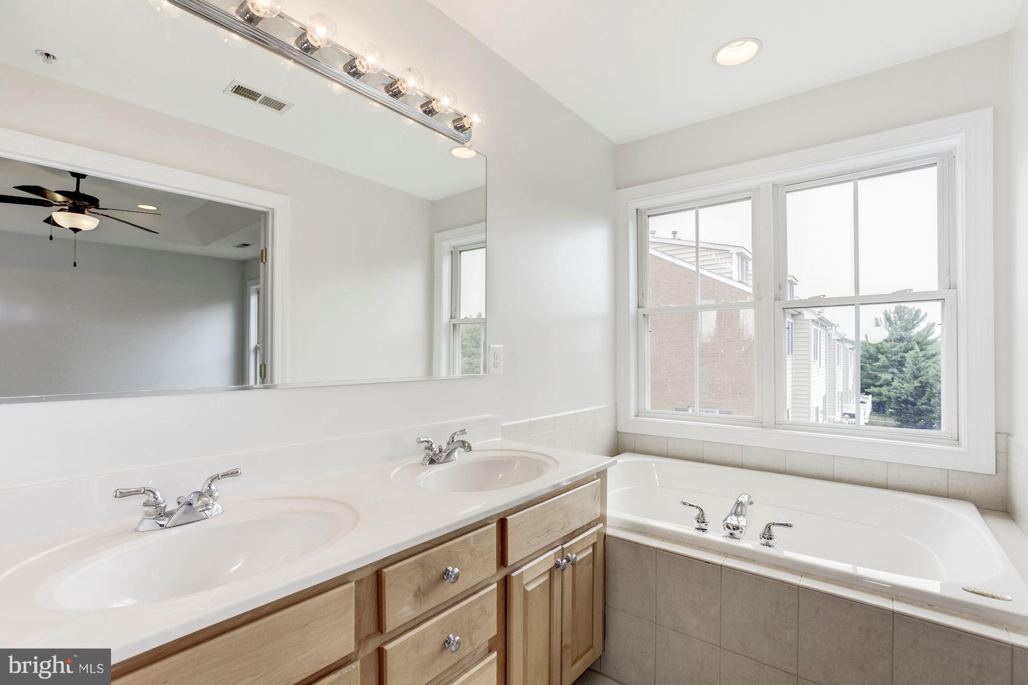 2316 Plyers Mill Road Silver Spring, MD 20902 - Photo 17 of 24 a bathroom with a tub a sink double vanity and window
