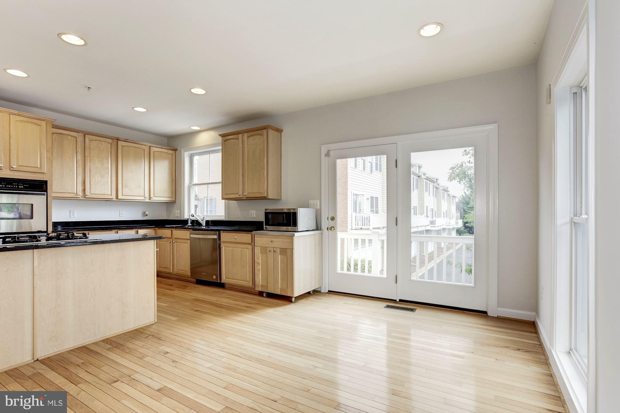 2316 Plyers Mill Road Silver Spring, MD 20902 - Photo 7 of 24 a large kitchen with granite countertop a stove a sink a refrigerator and white cabinets with wooden floor