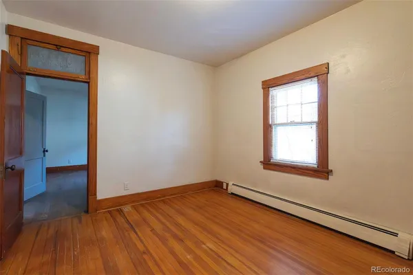 an empty room with wooden floor closet and windows