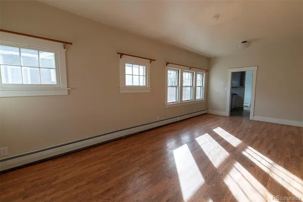 a view of empty room with wooden floor and fan