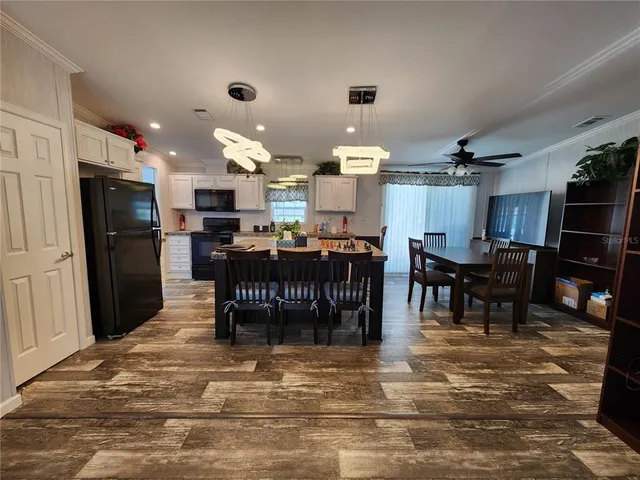 a kitchen with stainless steel appliances kitchen island granite countertop a dining table chairs and a refrigerator