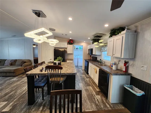 a kitchen with kitchen island granite countertop a sink cabinets and stainless steel appliances