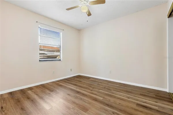a view of an empty room with wooden floor and a window