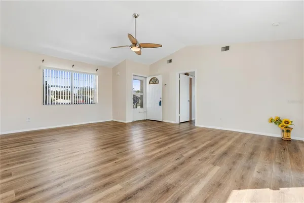 a view of an empty room with window and wooden floor