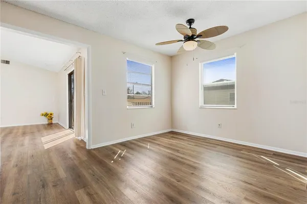 a view of empty room with wooden floor and fan