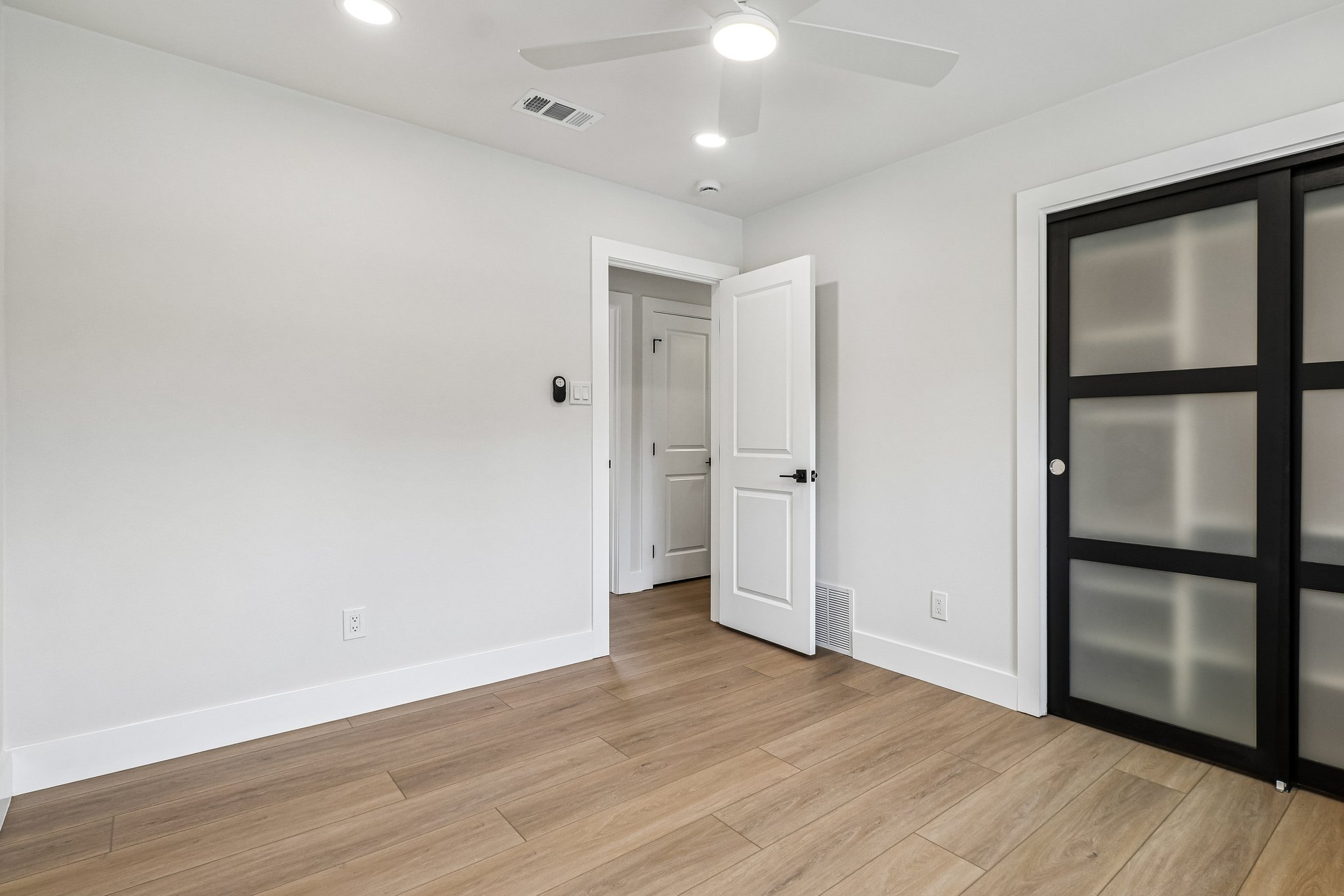 11809 Charing Cross Road Austin, TX 78759 - Photo 22 of 34 Blonde wood-look flooring enhances the crisp white walls and modern closet doors of this serene bedroom space.