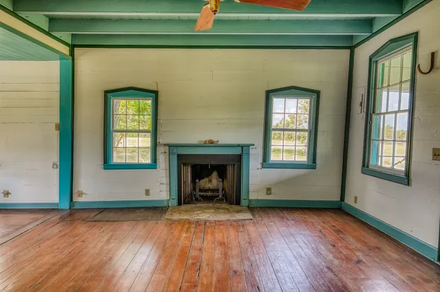 an empty room with wooden floor a fireplace and windows