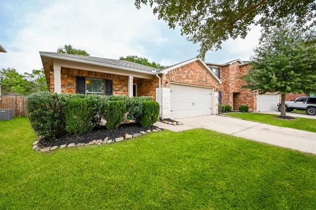 a view of a yard in front of a house with plants and large tree