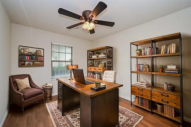 an empty room with wooden floor ceiling fan and windows