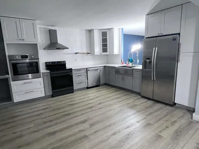 a kitchen with granite countertop a refrigerator and a stove top oven