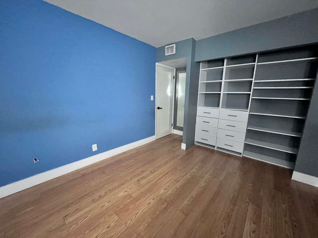 20441 Northeast 30th Avenue, Unit 110 Miami, FL 33180 - Photo 8 of 16 a view of an empty room with a wooden floor and a window