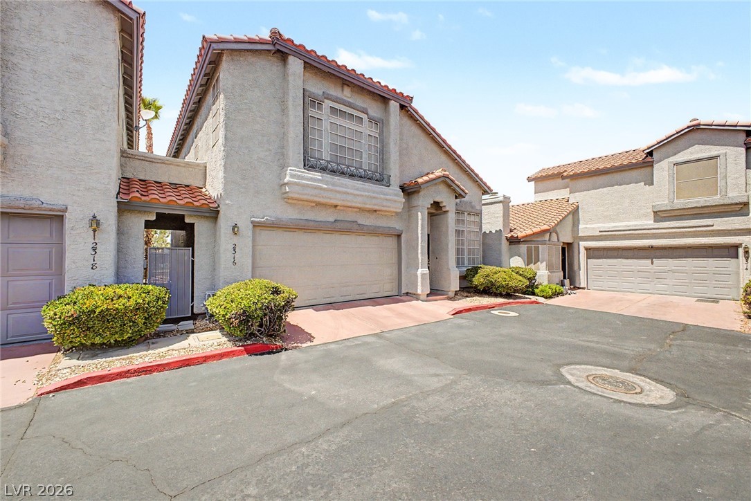 2316 Ramsgate Drive Henderson, NV 89074 - Photo 2 of 28 A Mediterranean-inspired exterior features stucco walls, tiled roofs, and integrated garages, creating inviting curb appeal.