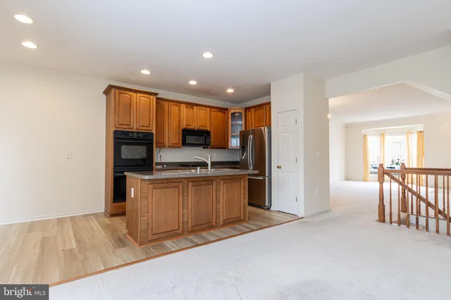 a kitchen with stainless steel appliances kitchen island granite countertop a refrigerator and a stove top oven