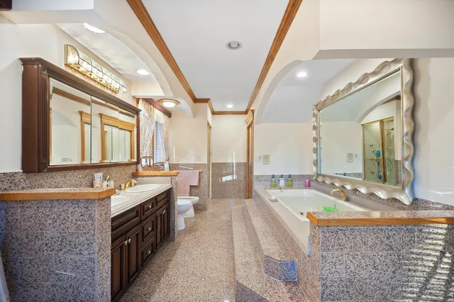 a spacious bathroom with a granite countertop tub double vanity and a large mirror