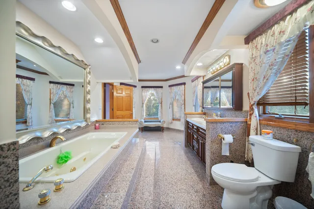a bathroom with a granite countertop sink a toilet a mirror and bathtub