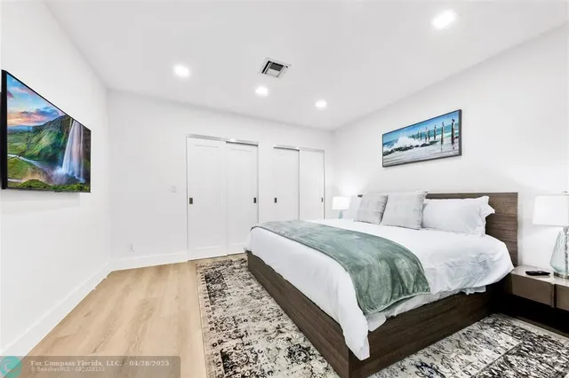 a spacious bedroom with a bed and a flat screen tv