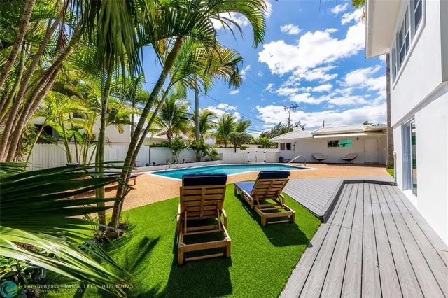 a view of swimming pool with chairs and wooden fence
