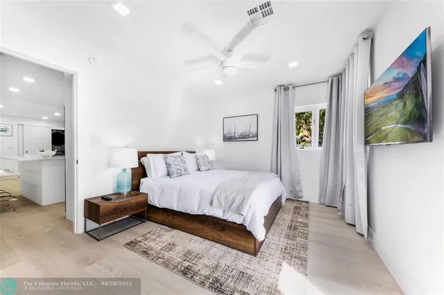 a spacious bedroom with a bed a mirror and a flat screen tv