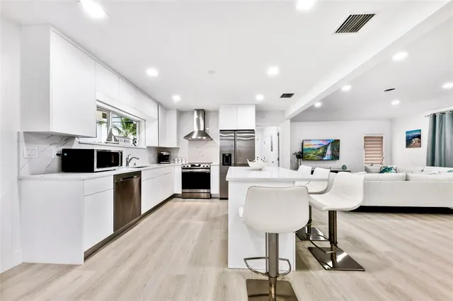 a living room with stainless steel appliances kitchen island granite countertop furniture a rug kitchen view and a chandelier