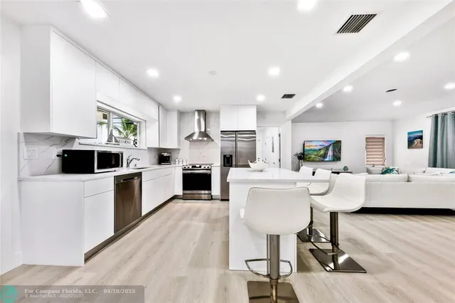 a living room with stainless steel appliances kitchen island granite countertop furniture a rug kitchen view and a chandelier