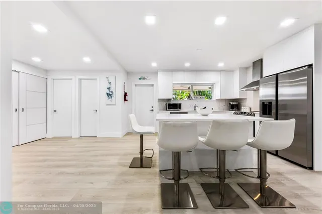 a kitchen with stainless steel appliances kitchen island granite countertop a sink and a refrigerator