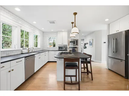 a kitchen with stainless steel appliances granite countertop a sink a stove a refrigerator and island with wooden floor
