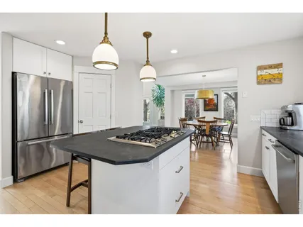 a kitchen with stainless steel appliances granite countertop a stove a refrigerator a kitchen island a sink dishwasher and a refrigerator with wooden floor