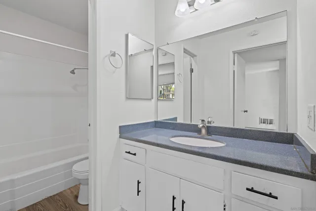 a bathroom with a granite countertop sink a toilet and shower