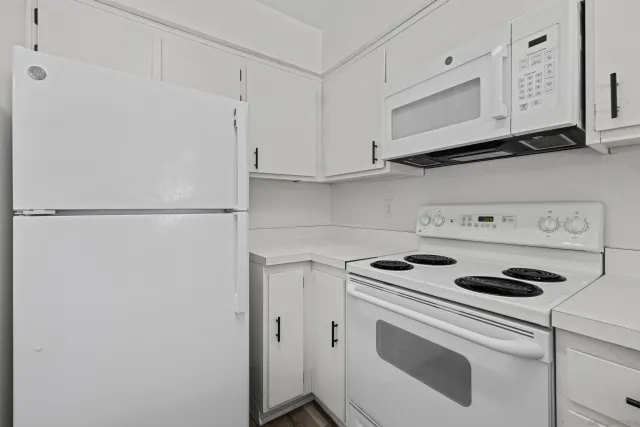 a kitchen with white cabinets and white appliances