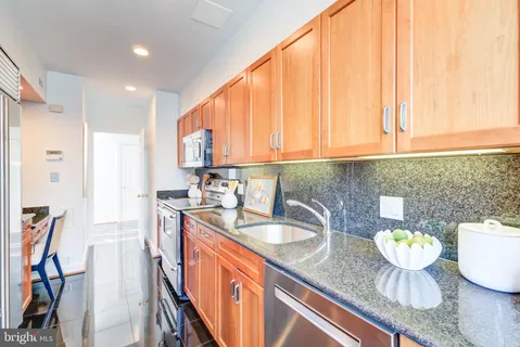 a kitchen with stainless steel appliances granite countertop a sink a stove and a wooden cabinets