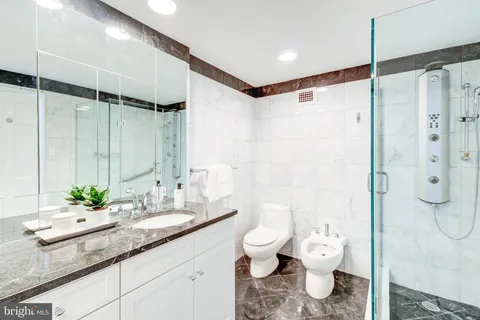 a bathroom with a granite countertop sink a toilet and shower