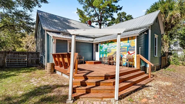 a view of a patio with table and chairs with wooden fence and large trees