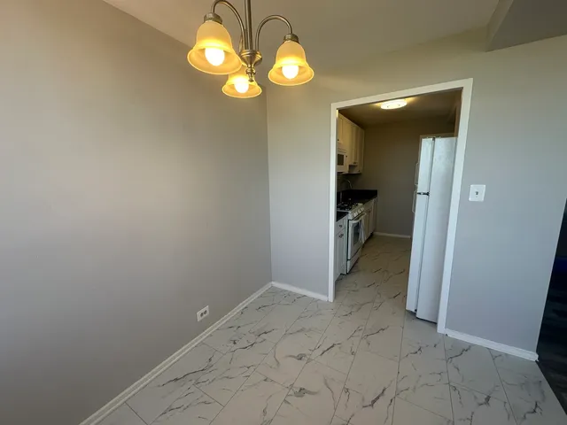a view of a hallway with wooden floor and a chandelier
