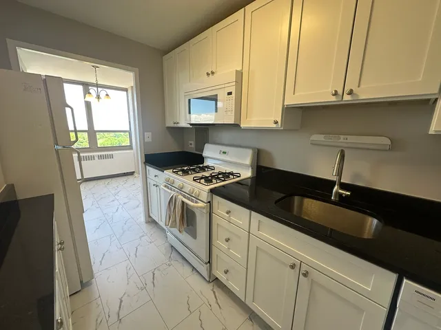 a kitchen with granite countertop a sink a stove and cabinets