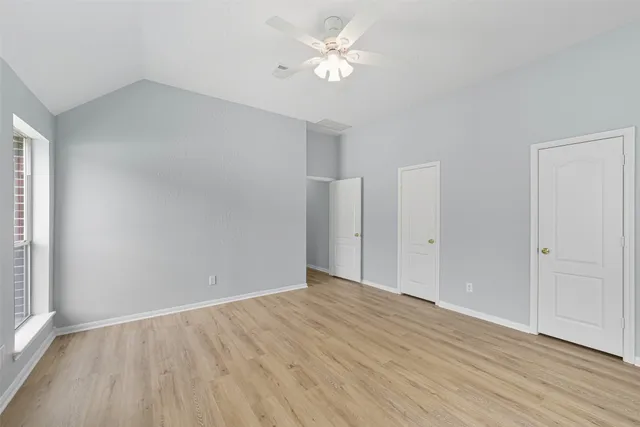 an empty room with wooden floor and a ceiling fan