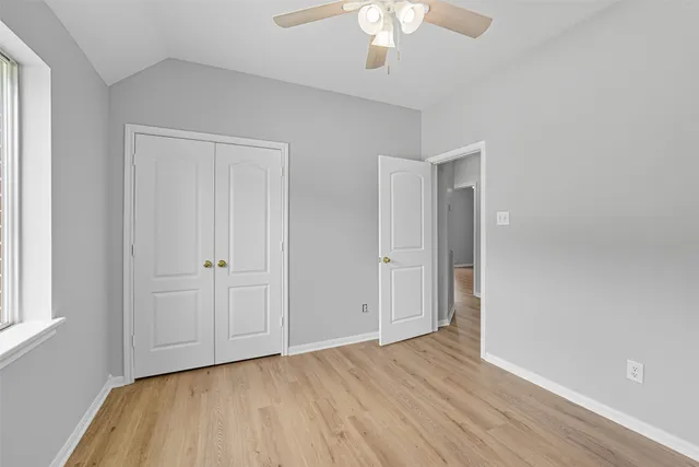 an empty room with wooden floor chandelier fan and windows