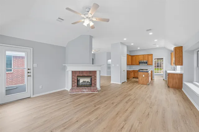 an empty room with wooden floor fireplace and windows