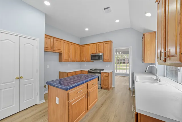 a kitchen that has a lot of cabinets stainless steel appliances and a large window