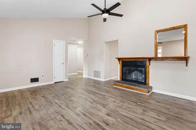 a view of an empty room with wooden floor fireplace and a window