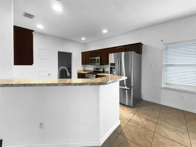 a kitchen with stainless steel appliances granite countertop a refrigerator and a stove top oven