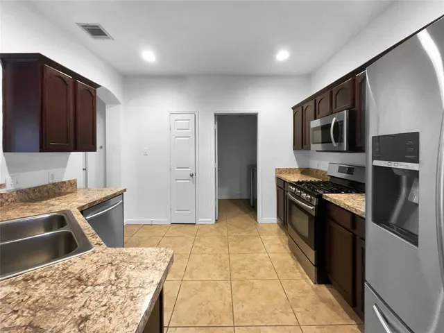 a kitchen with stainless steel appliances granite countertop a refrigerator and a stove top oven