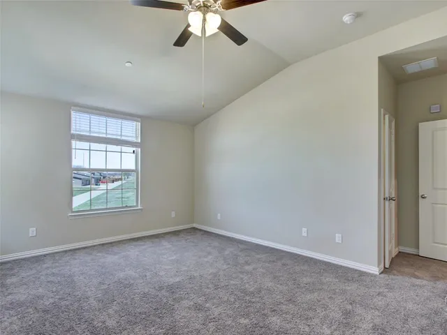 an empty room with chandelier fan and windows