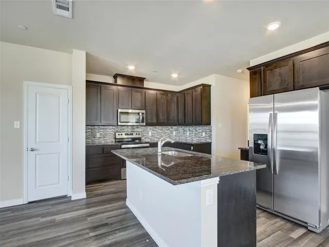 a kitchen with stainless steel appliances granite countertop a refrigerator a sink and a stove