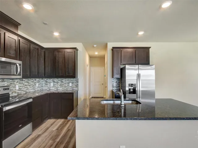 a kitchen with stainless steel appliances granite countertop a sink and a stove top oven with wooden floor