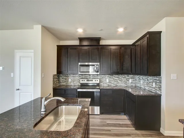 a kitchen with kitchen island granite countertop a sink stove and refrigerator
