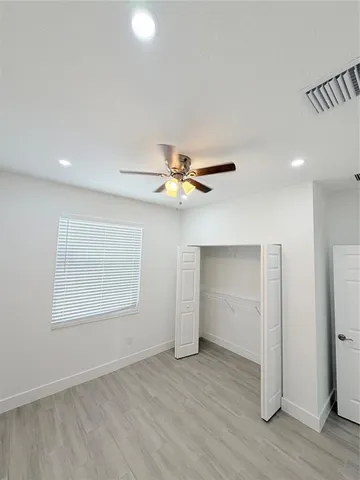 a view of empty room with wooden floor and fan